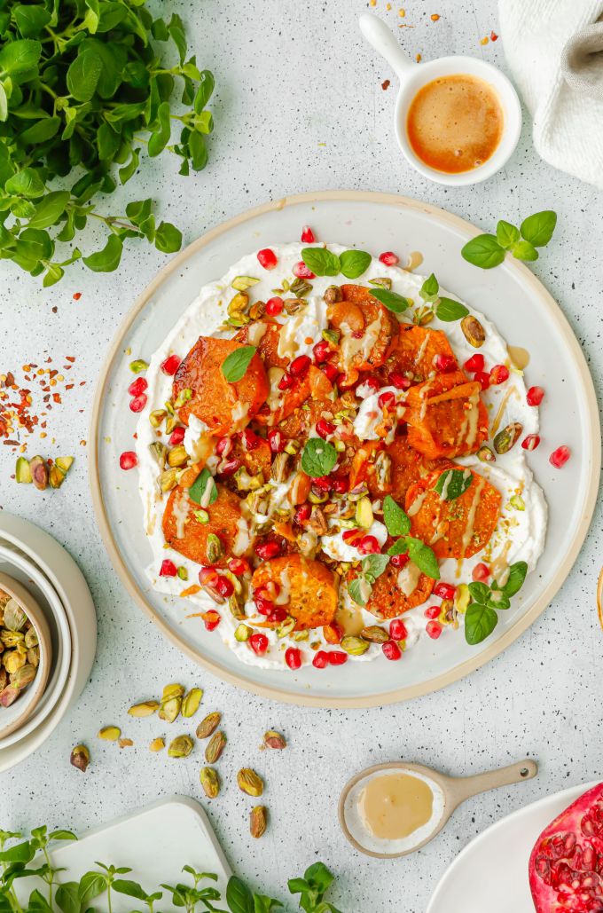 Pieczone plastry batatów na sosie śmietanowo-parmezanowym, z pistacjami, oregano, granatem i masłem chili